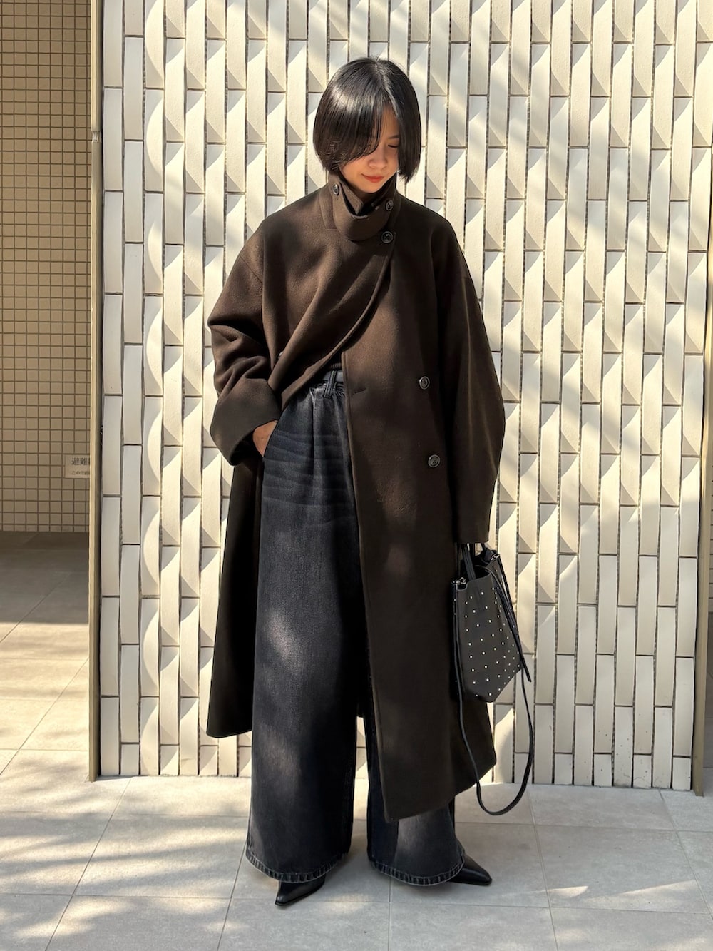 グリーン系のチェスターコート、ブラック系のニット/セーター、ブラック系のデニムパンツを着用したレディースの冬コーディネートの4枚目の写真