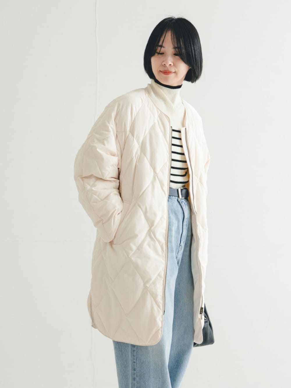 ホワイト系のダウンジャケット/コート、ホワイト系のニット/セーター、ブラック系のハンドバッグを着用したレディースの冬コーディネートの2枚目の写真