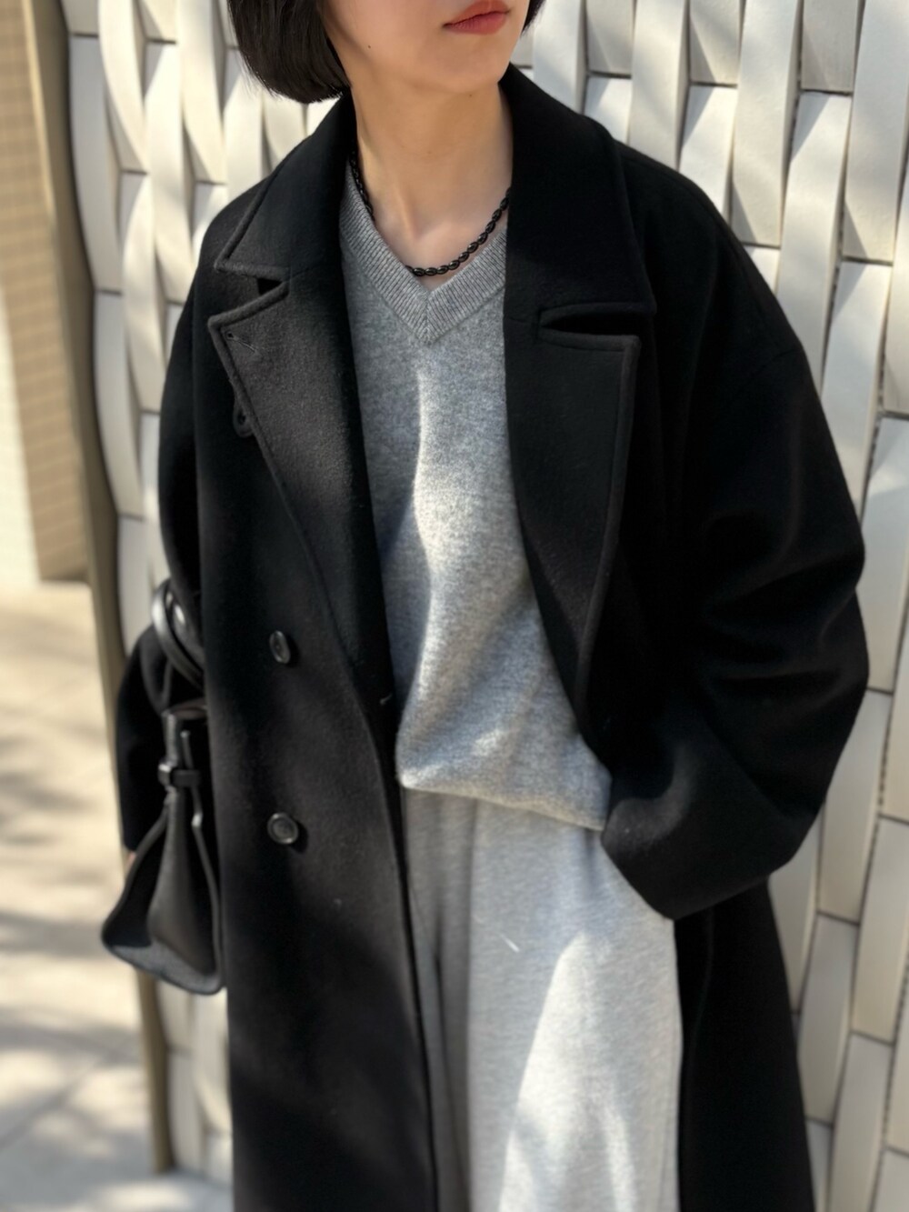 ブラック系のトートバッグ、ブラック系のチェスターコート、グリーン系のニット/セーターを着用したレディースの冬コーディネートの3枚目の写真