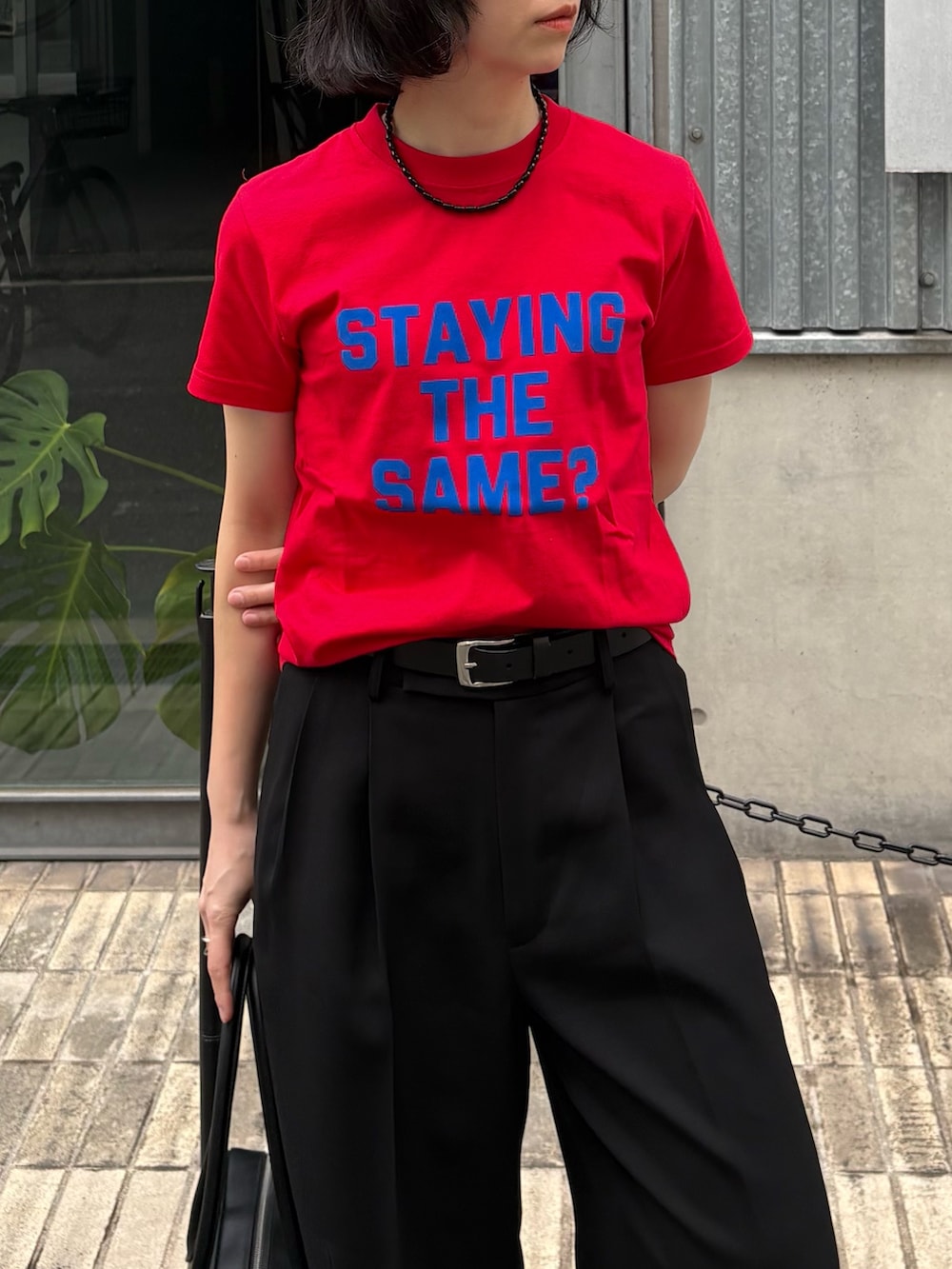 ブラック系のその他パンツ、ブラック系のショルダーバッグ、レッド系のTシャツ/カットソーを着用したレディースの冬コーディネートの4枚目の写真