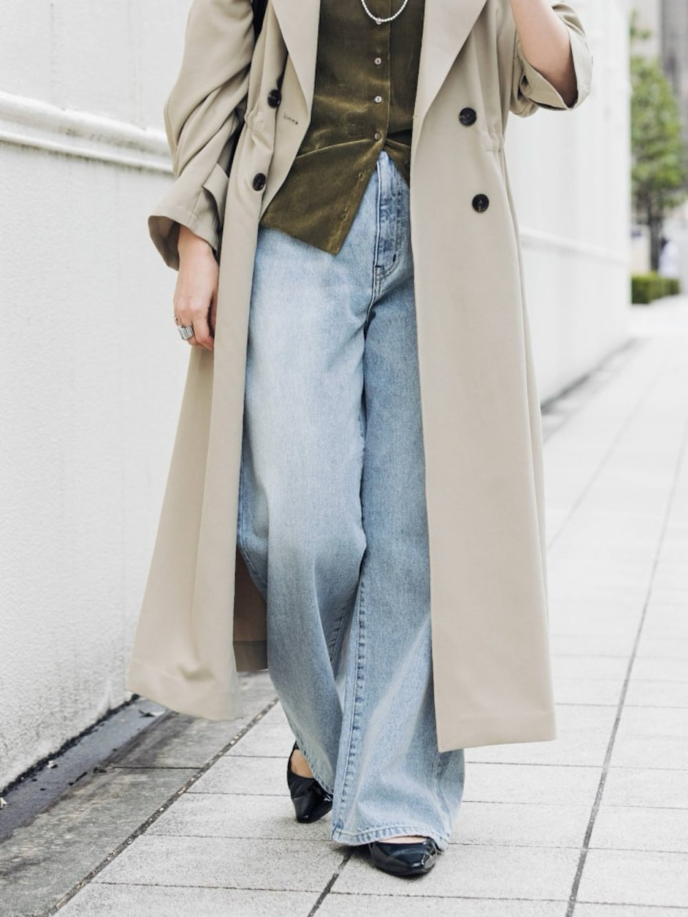 ベージュ系のトレンチコート、グリーン系のカーディガン/ボレロ、ブルー系のデニムパンツを着用したレディースの冬コーディネートの6枚目の写真