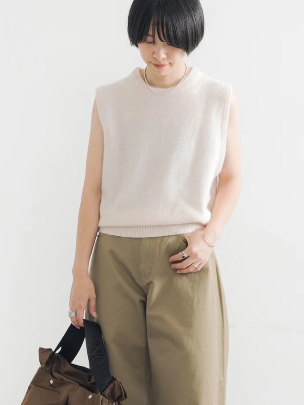 ホワイト系のベスト、ブラウン系のショルダーバッグ、ベージュ系のその他パンツを着用したレディースの夏コーディネートの3枚目の写真