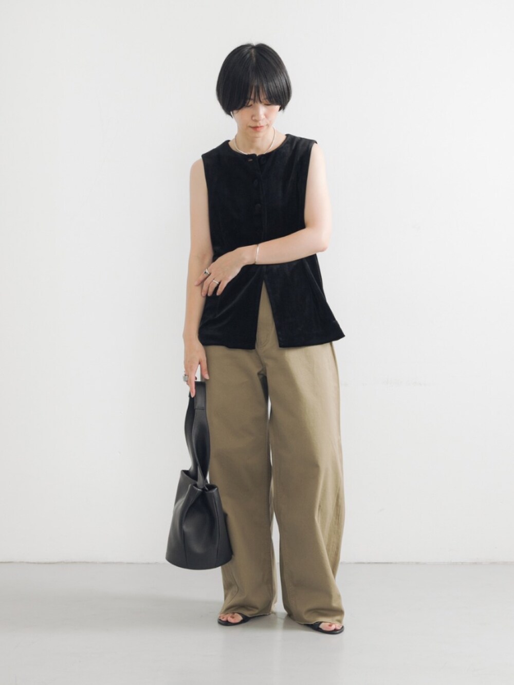 ブラック系のベスト、ベージュ系のその他パンツ、ブラック系のハンドバッグを着用したレディースの夏コーディネートの2枚目の写真
