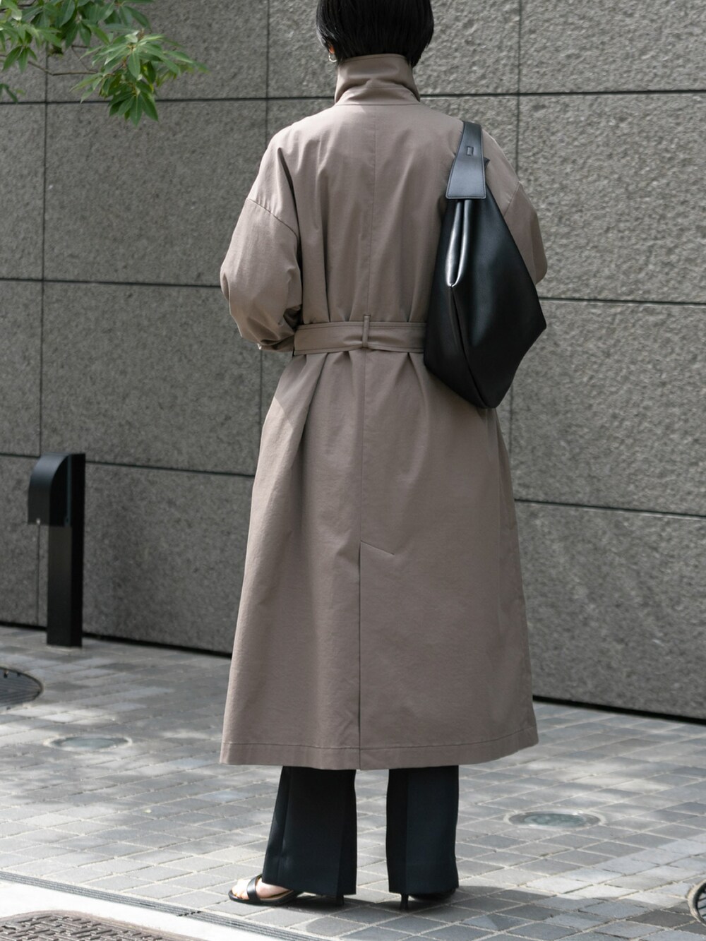 ブラウン系のステンカラーコート、ブラック系のその他パンツを着用したレディースの春コーディネートの2枚目の写真