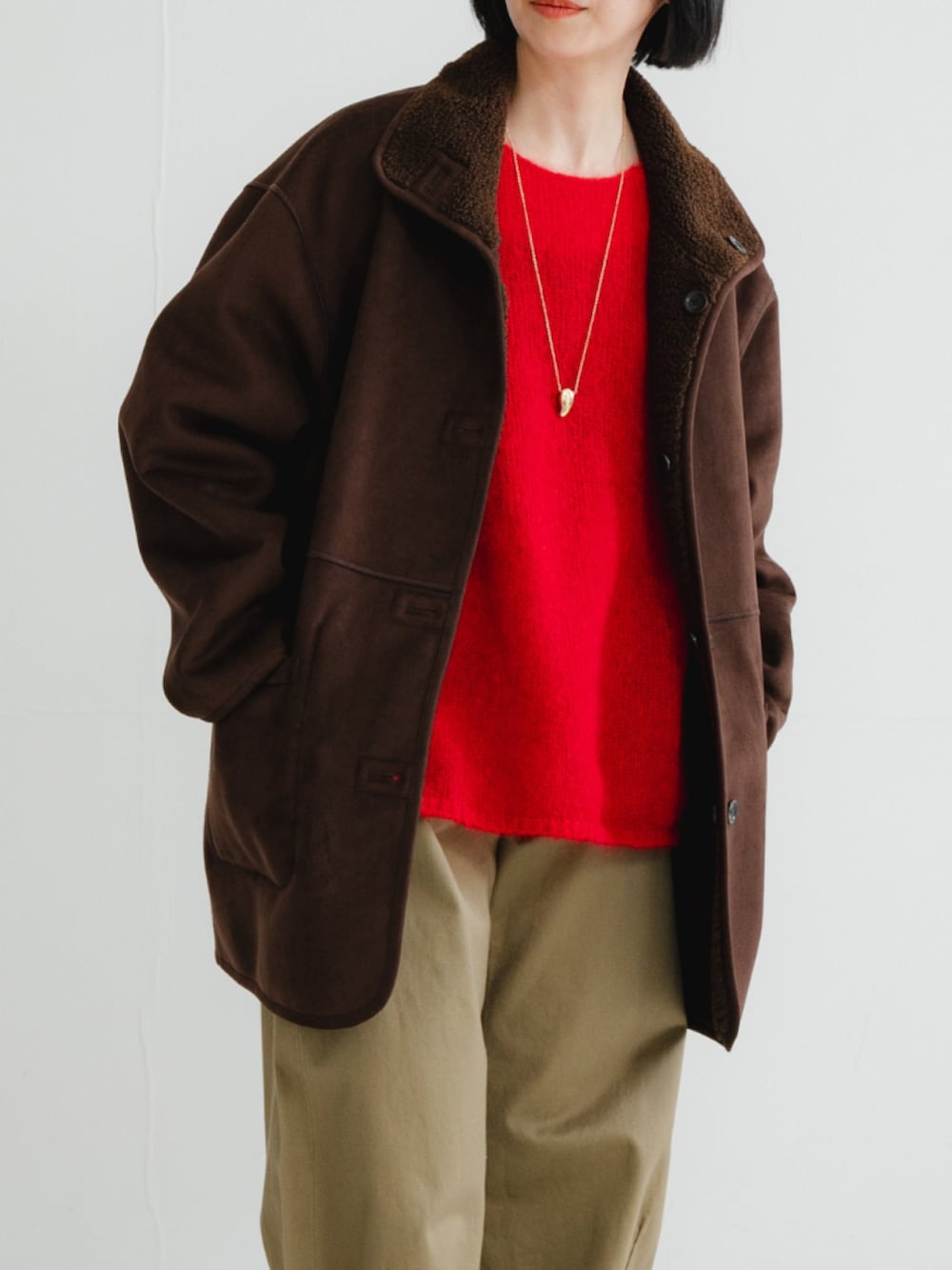 ブラウン系のムートンコート、ブラウン系のニット/セーター、ベージュ系のその他パンツを着用したレディースの冬コーディネートの2枚目の写真