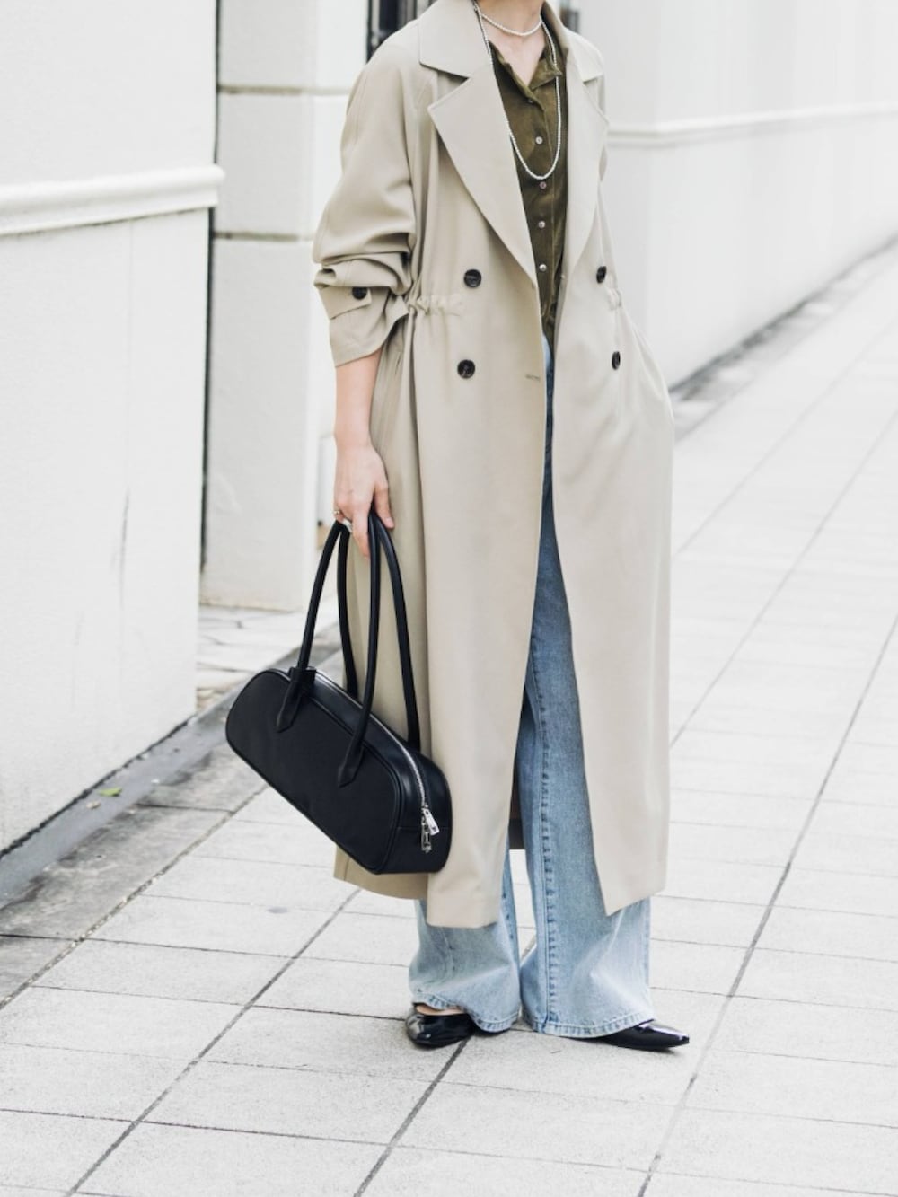 ベージュ系のトレンチコート、グリーン系のカーディガン/ボレロ、ブルー系のデニムパンツを着用したレディースの冬コーディネートの3枚目の写真