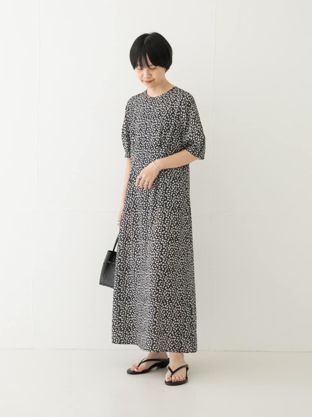 ホワイト系のワンピース、ブラック系のトートバッグ、ブラック系のサンダルを着用したレディースの夏コーディネートの2枚目の写真