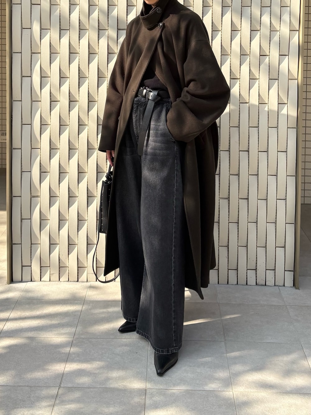 グリーン系のチェスターコート、ブラック系のニット/セーター、ブラック系のデニムパンツを着用したレディースの冬コーディネートの5枚目の写真