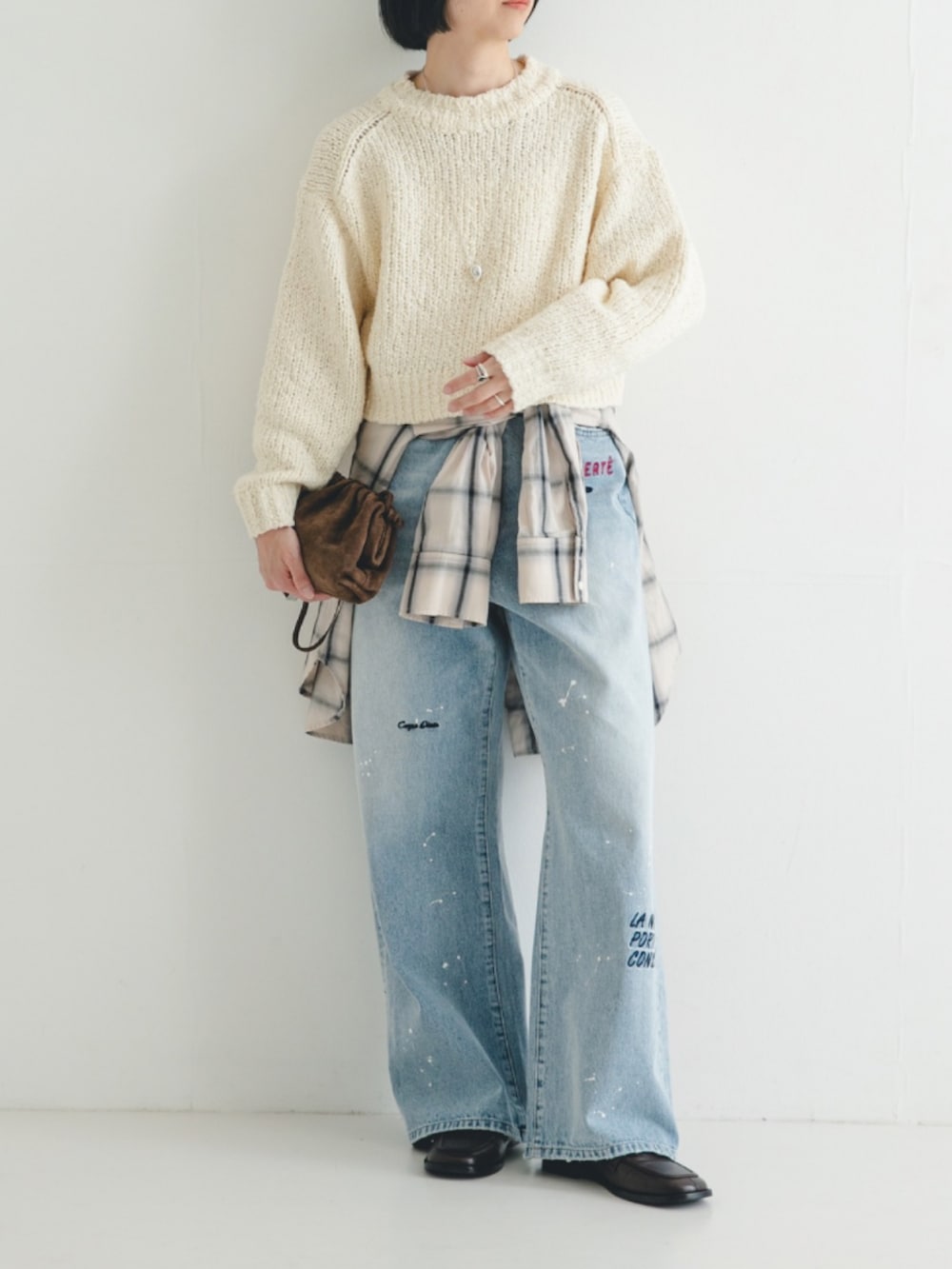 ホワイト系のニット/セーター、ホワイト系のシャツ/ブラウス、ブルー系のデニムパンツを着用したレディースの冬コーディネートの2枚目の写真