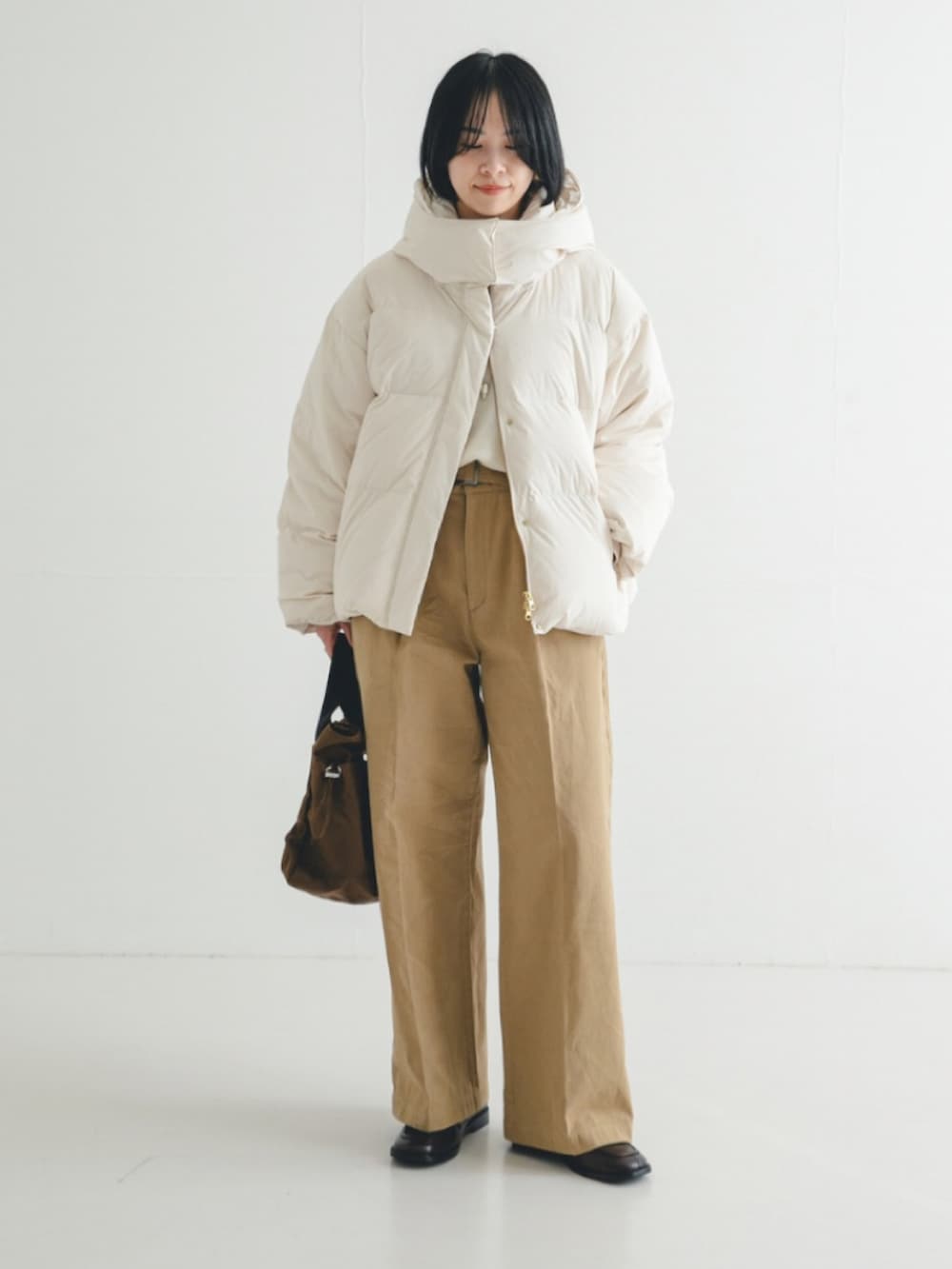 ホワイト系のダウンジャケット/コート、ホワイト系のニット/セーター、ブラウン系のショルダーバッグを着用したレディースの冬コーディネートの2枚目の写真