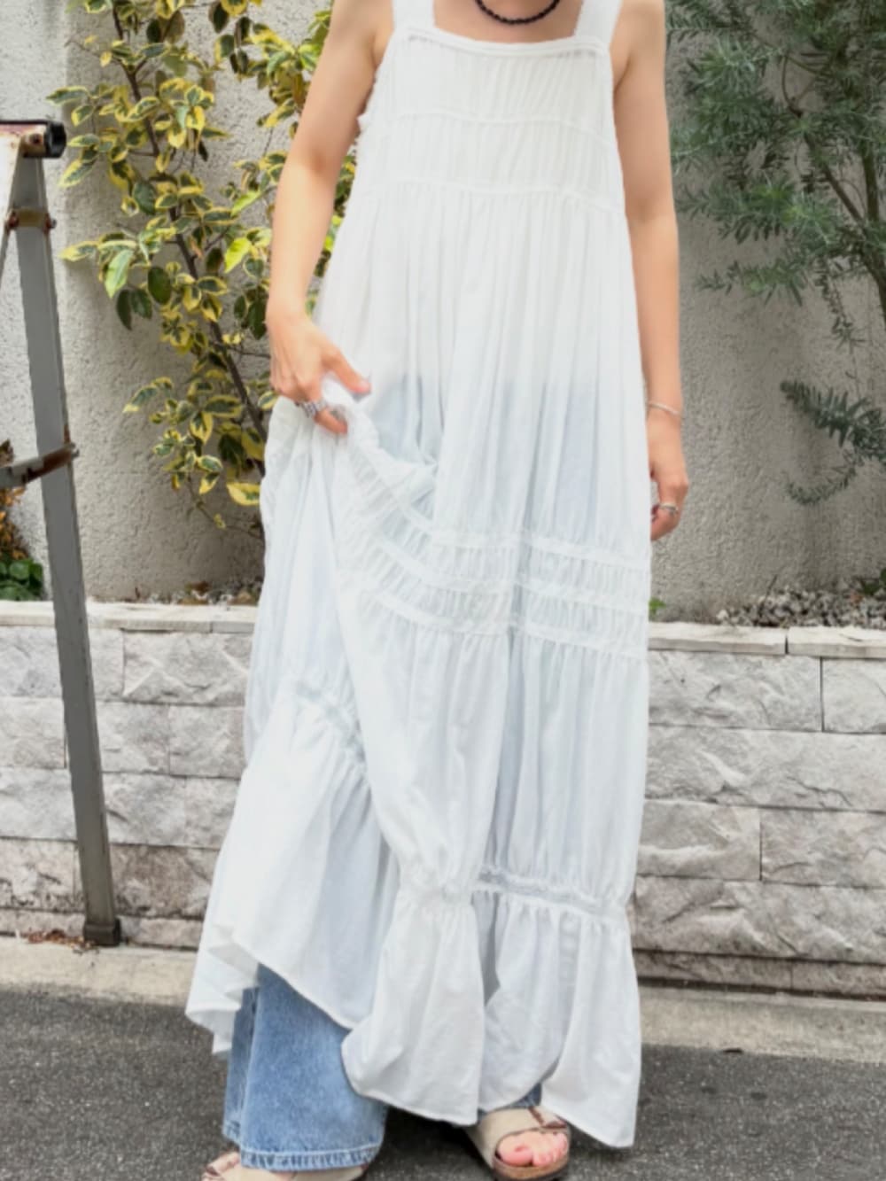 ホワイト系のワンピース、ブルー系のデニムパンツ、ベージュ系のサンダルを着用したレディースの夏コーディネートの4枚目の写真