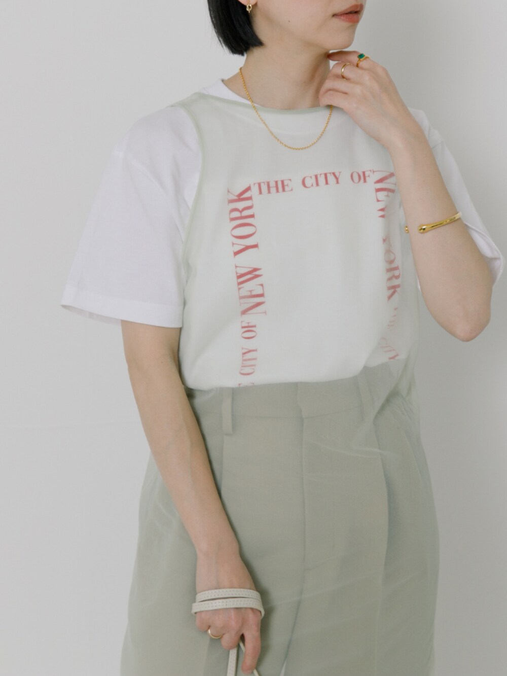 グリーン系のワンピース、ホワイト系のTシャツ/カットソー、ホワイト系のショルダーバッグを着用したレディースの冬コーディネートの3枚目の写真