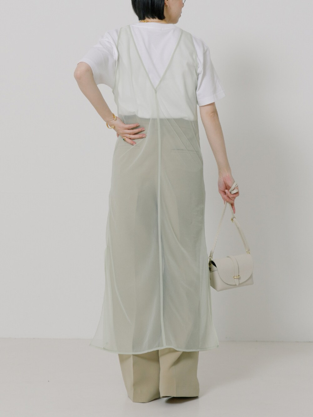 グリーン系のワンピース、ホワイト系のTシャツ/カットソー、ホワイト系のショルダーバッグを着用したレディースの冬コーディネートの2枚目の写真