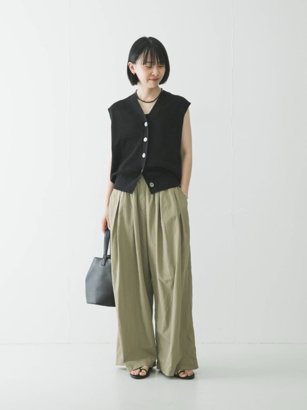 ベージュ系のその他パンツ、ブラック系のハンドバッグ、ブラック系のサンダルを着用したレディースの春コーディネートの2枚目の写真