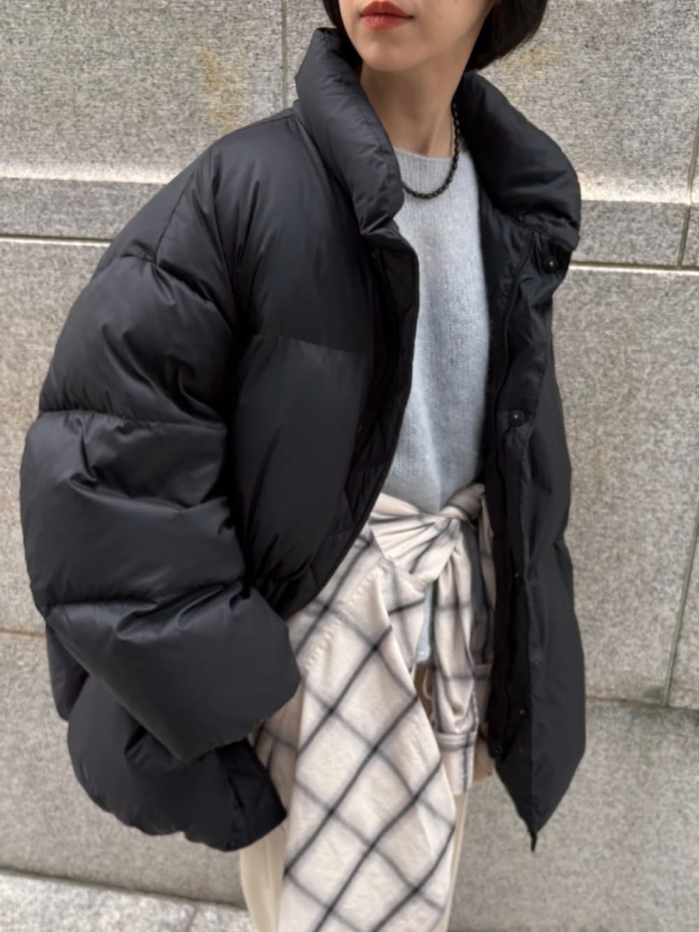 ベージュ系のブーツ、ブルー系のニット/セーター、ブラック系のダウンジャケット/コートを着用したレディースの秋コーディネートの3枚目の写真