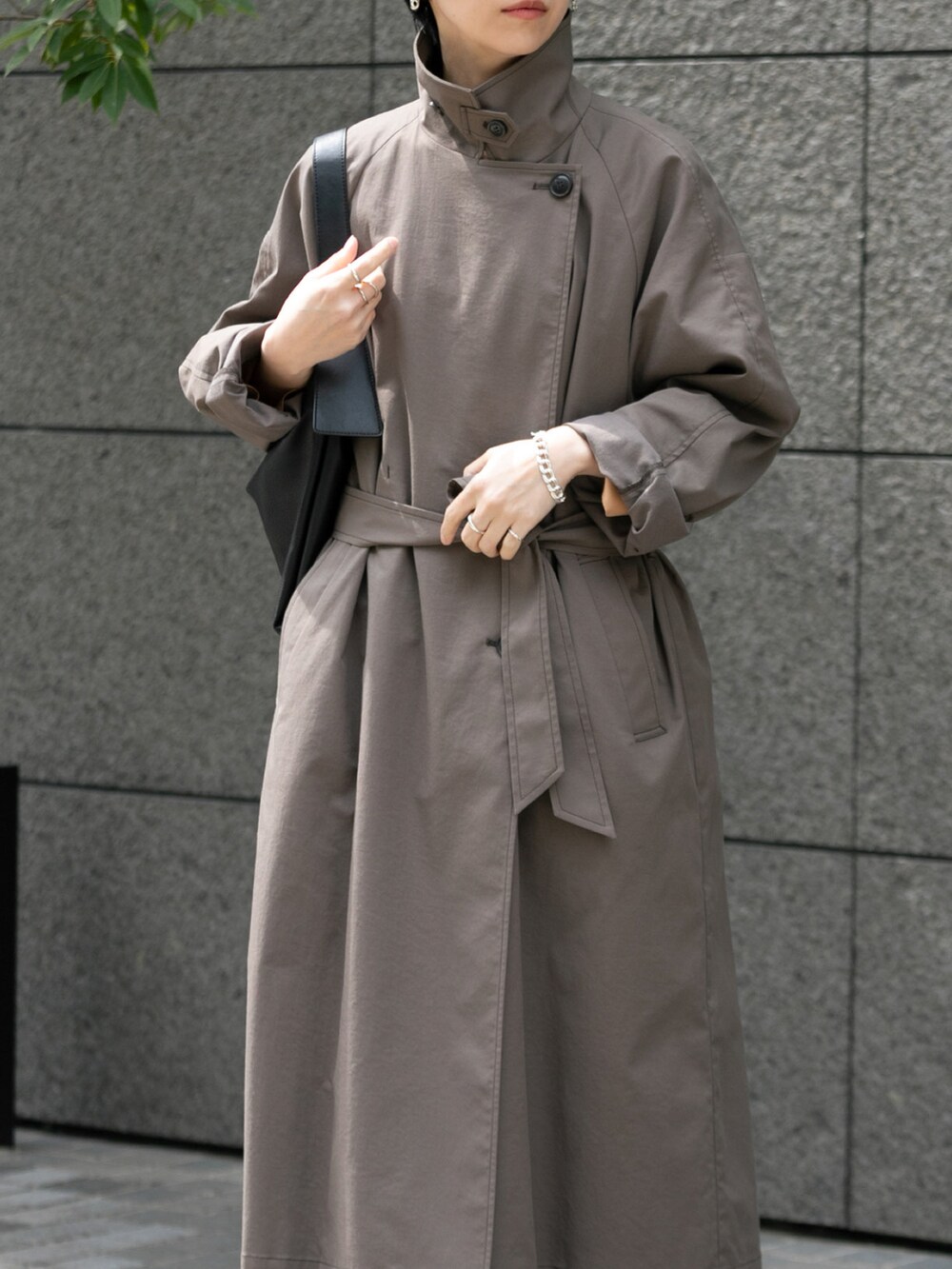 ブラウン系のステンカラーコート、ブラック系のその他パンツを着用したレディースの春コーディネートの3枚目の写真