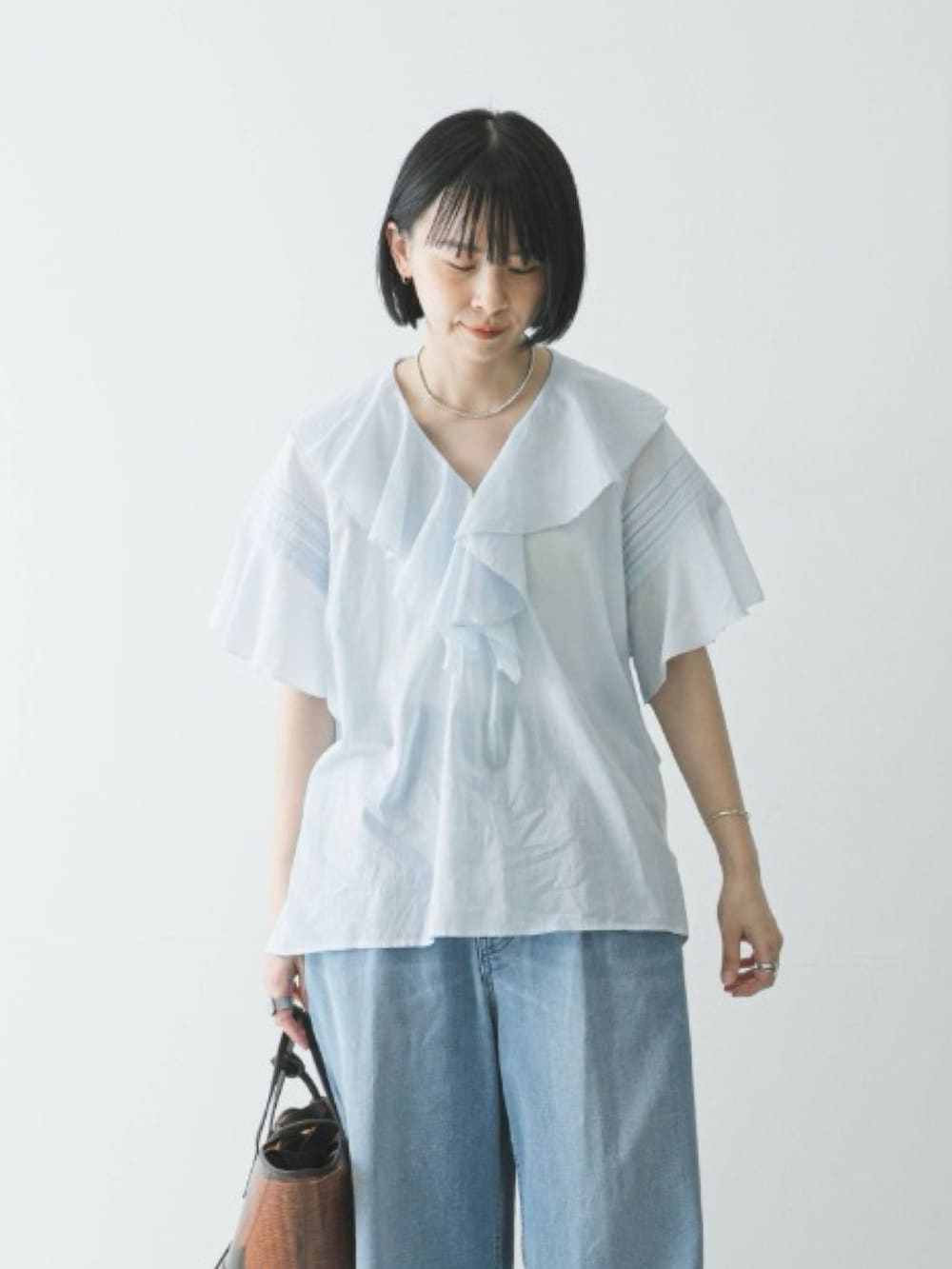 ブルー系のシャツ/ブラウス、ブルー系のデニムパンツ、ブラウン系のかごバッグを着用したレディースの春コーディネートの3枚目の写真