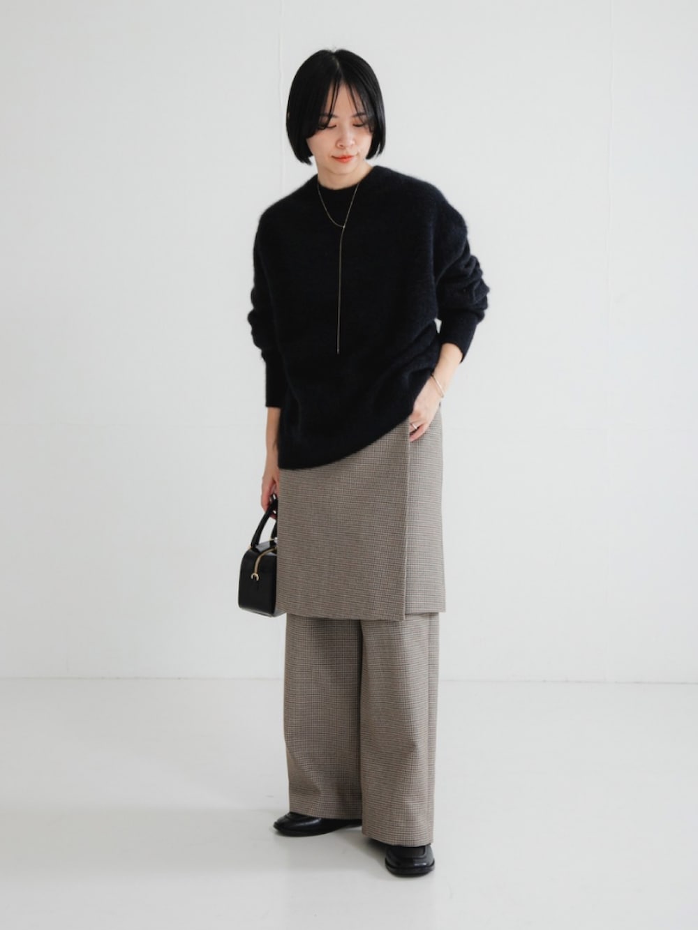 ブラック系のニット/セーター、グリーン系のその他パンツ、ブラック系のショルダーバッグを着用したレディースの冬コーディネートの2枚目の写真