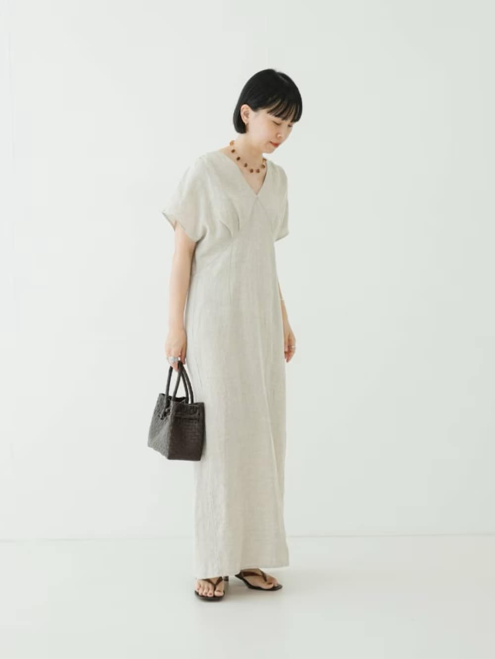ベージュ系のワンピース、ブラウン系のトートバッグ、ブラウン系のサンダルを着用したレディースの夏コーディネートの2枚目の写真