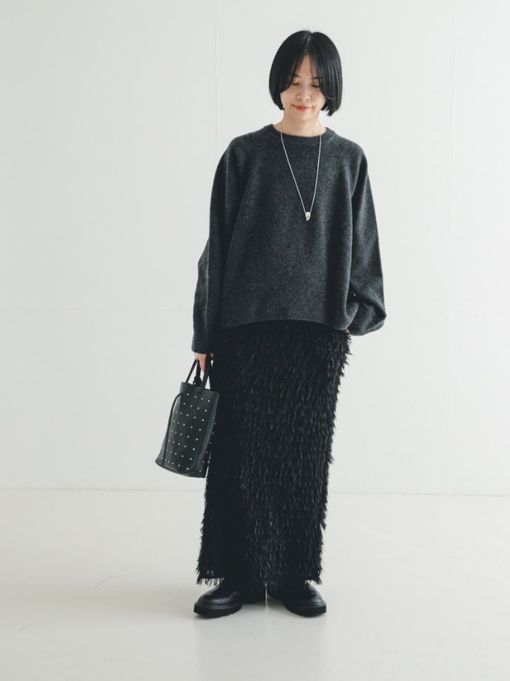 グレー系のニット/セーター、ブラック系のブーツ、ブラック系のトートバッグを着用したレディースの冬コーディネートの2枚目の写真