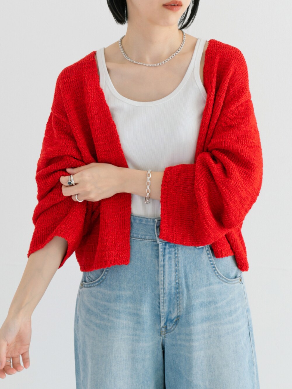 レッド系のカーディガン/ボレロ、ブルー系のデニムパンツ、シルバー系のブレスレットを着用したレディースの春コーディネートの3枚目の写真