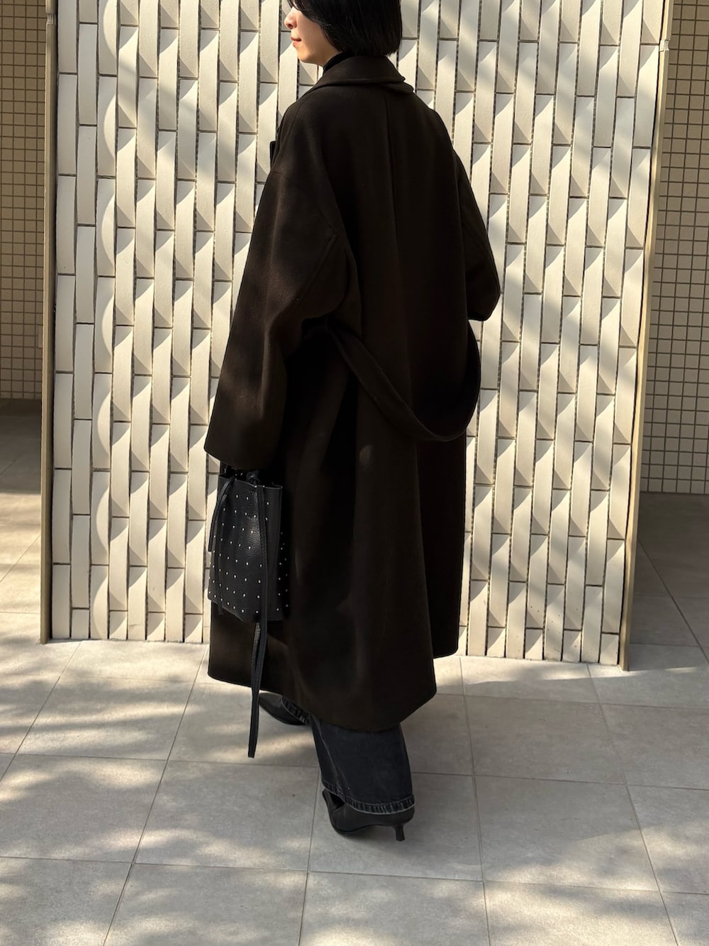 グリーン系のチェスターコート、ブラック系のニット/セーター、ブラック系のデニムパンツを着用したレディースの冬コーディネートの3枚目の写真