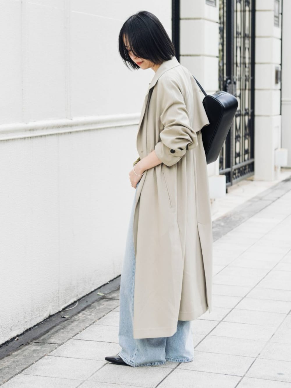 ベージュ系のトレンチコート、グリーン系のカーディガン/ボレロ、ブルー系のデニムパンツを着用したレディースの冬コーディネートの4枚目の写真