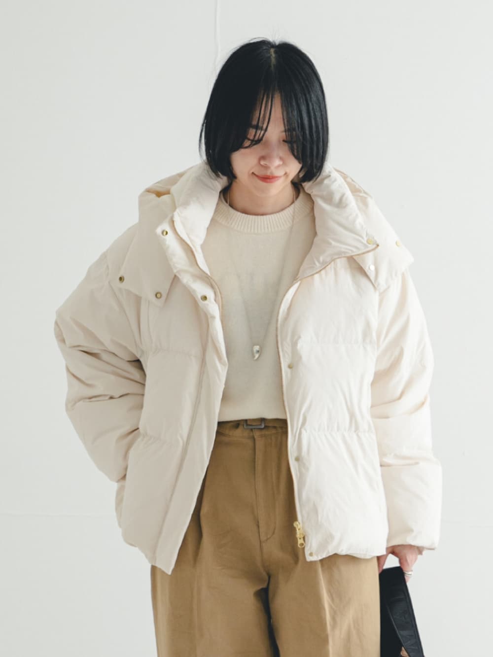 ホワイト系のダウンジャケット/コート、ホワイト系のニット/セーター、ブラウン系のショルダーバッグを着用したレディースの冬コーディネートの3枚目の写真