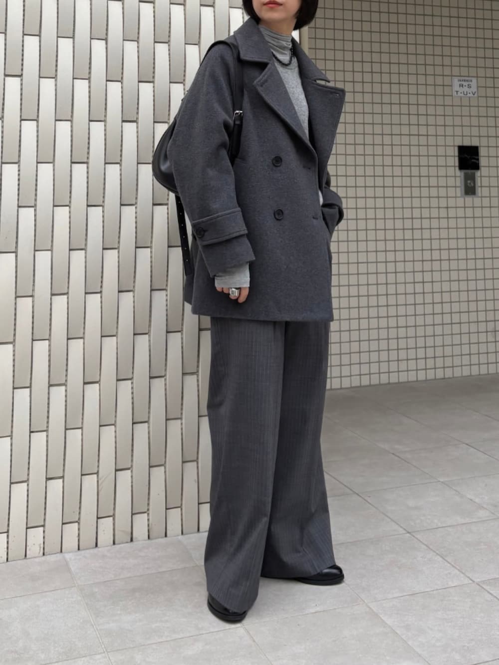 グレー系のピーコート、グリーン系のニット/セーター、グレー系のその他パンツを着用したレディースの秋コーディネートの3枚目の写真