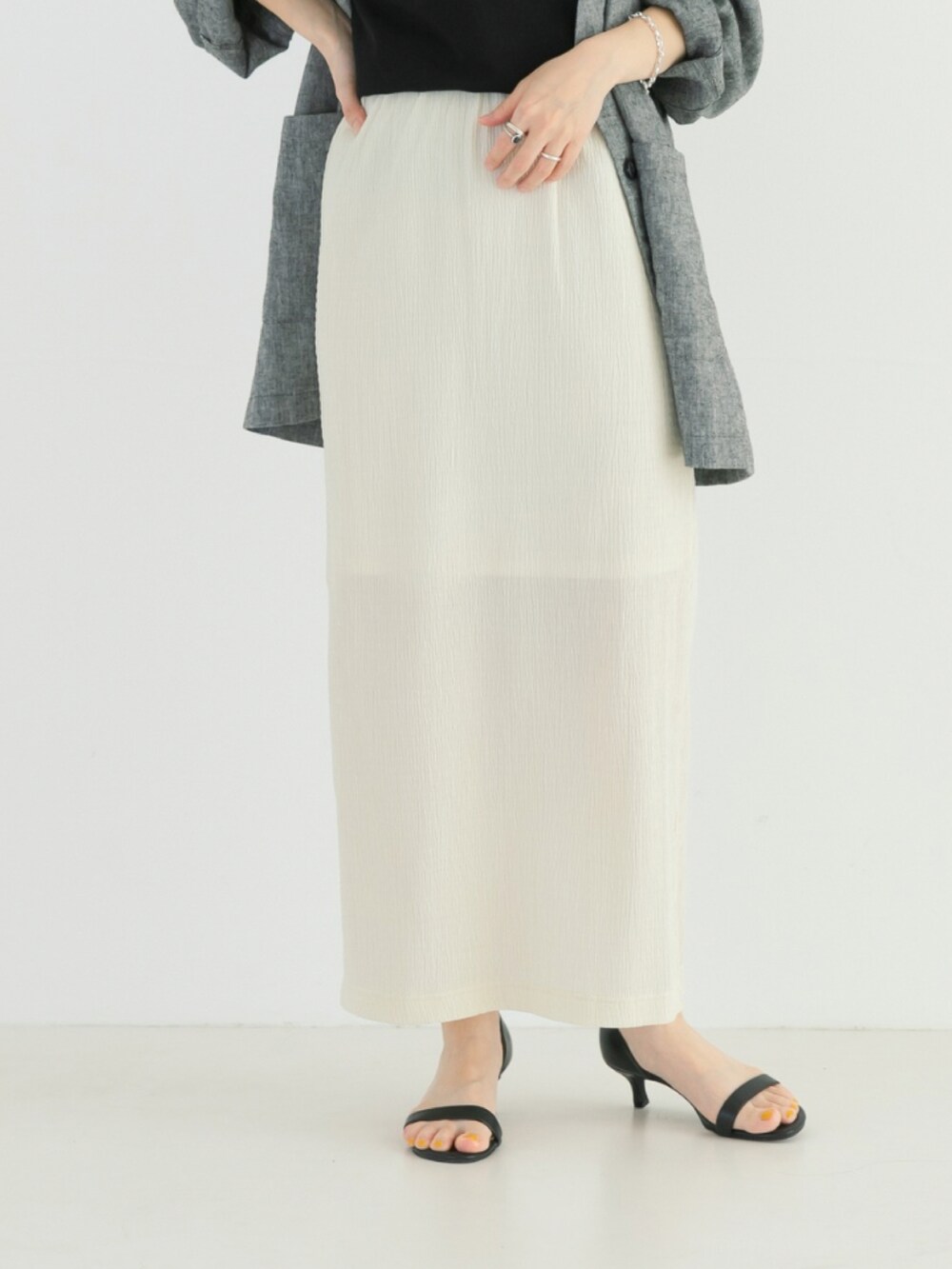 ブラック系のタンクトップ、ブラック系のノーカラージャケット、ホワイト系のスカートを着用したレディースの春コーディネートの4枚目の写真