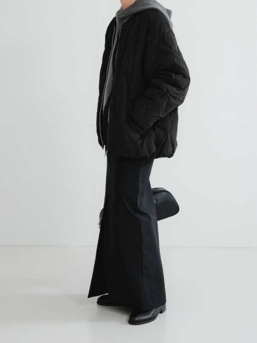 ブラック系のダウンジャケット/コート、グレー系のニット/セーター、ブラック系のスカートを着用したレディースの冬コーディネートの2枚目の写真