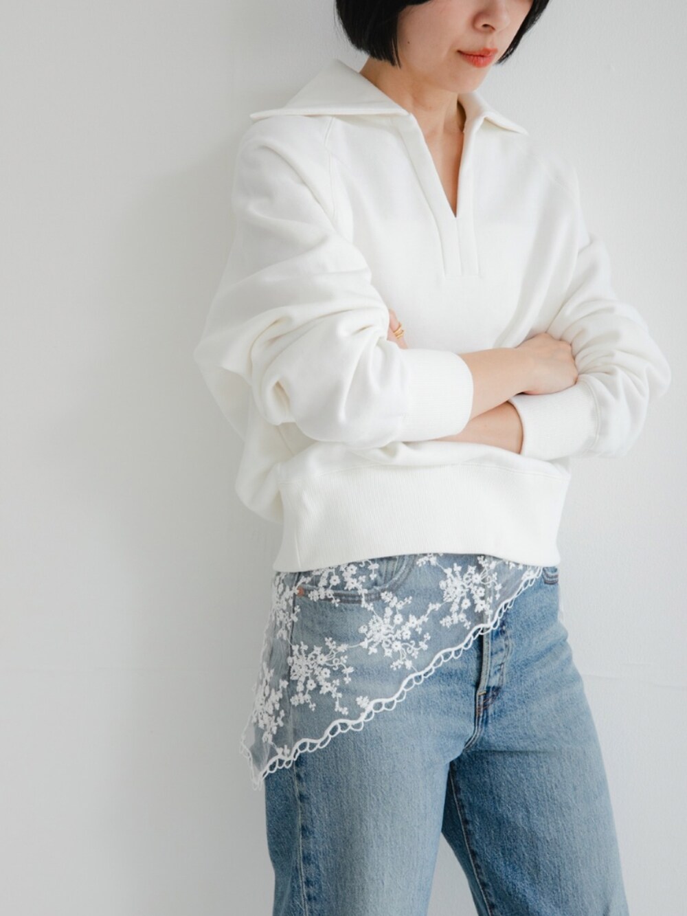 ホワイト系のスウェット、ブルー系のデニムパンツを着用したレディースの冬コーディネートの2枚目の写真