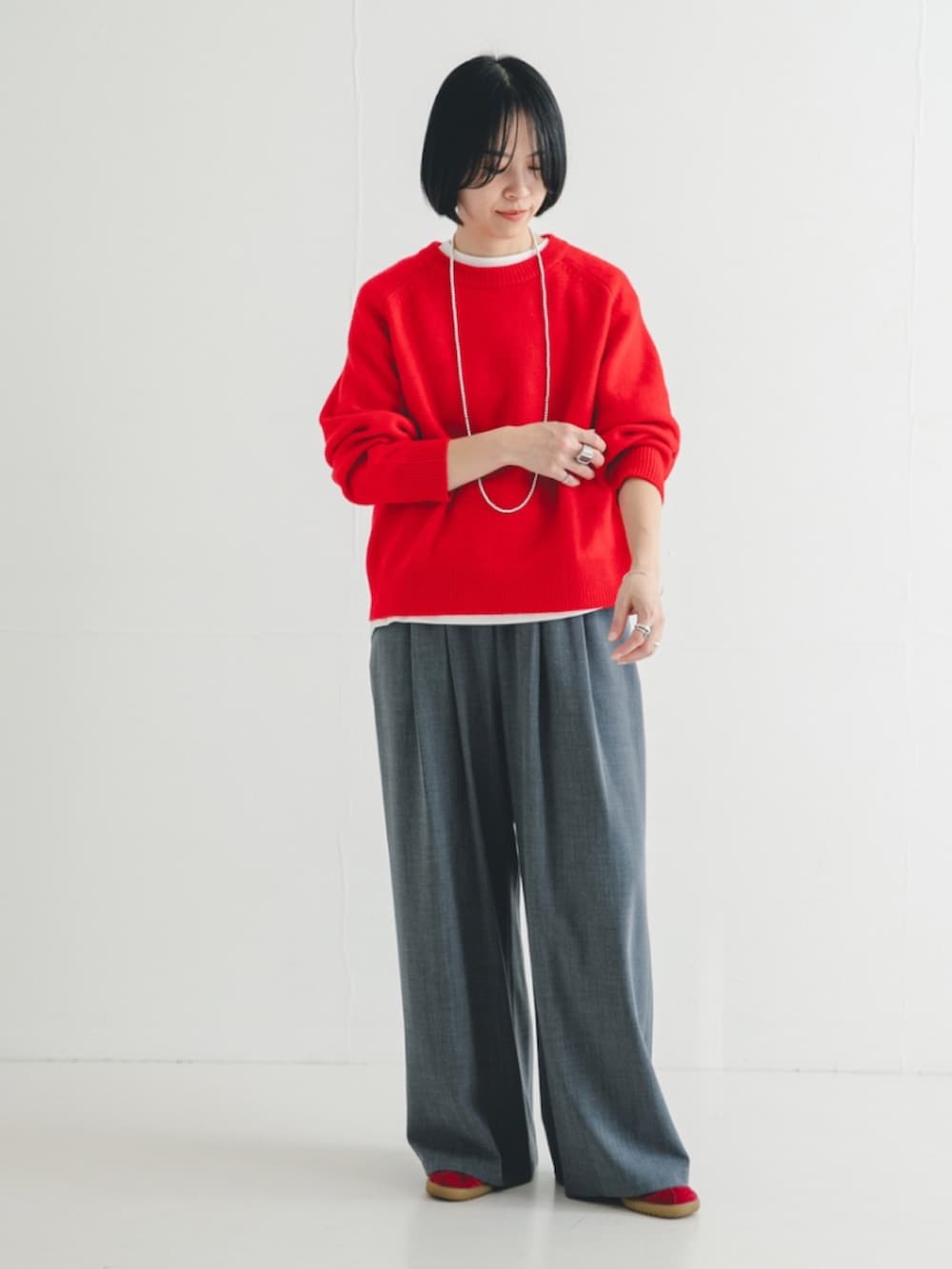 レッド系のニット/セーター、グレー系のその他パンツを着用したレディースの冬コーディネートの2枚目の写真