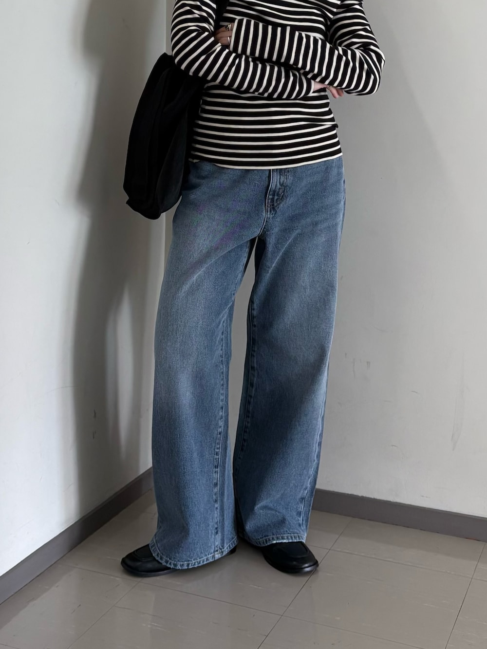 ブルー系のデニムパンツ、ブラック系のトートバッグ、ブラック系のTシャツ/カットソーを着用したレディースの夏コーディネートの3枚目の写真