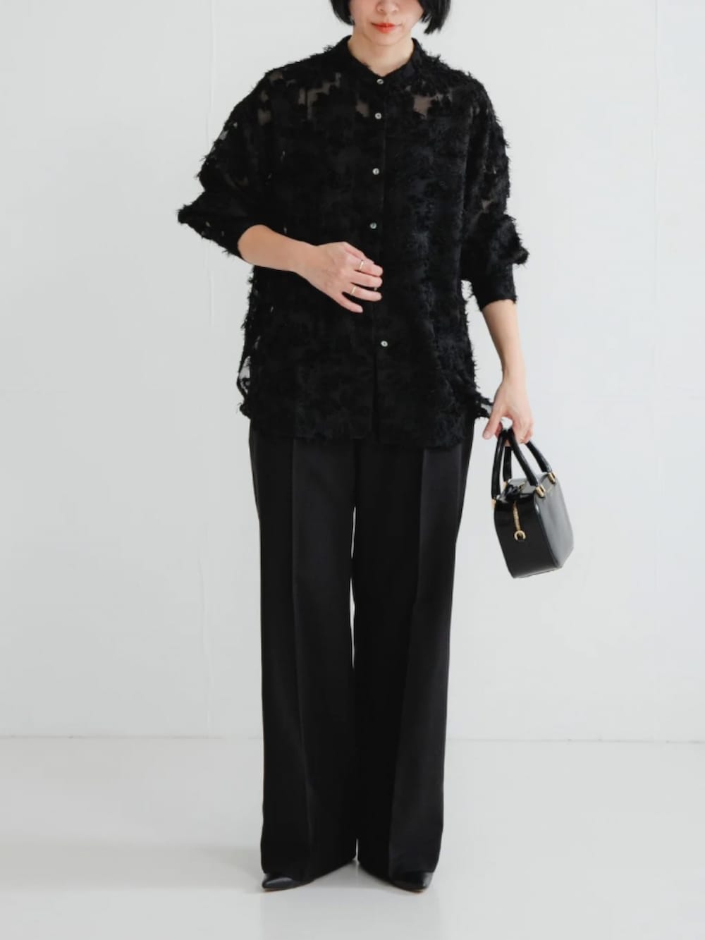 ブラック系のシャツ/ブラウス、ブラック系のスラックス、ブラック系のショルダーバッグを着用したレディースの冬コーディネートの2枚目の写真