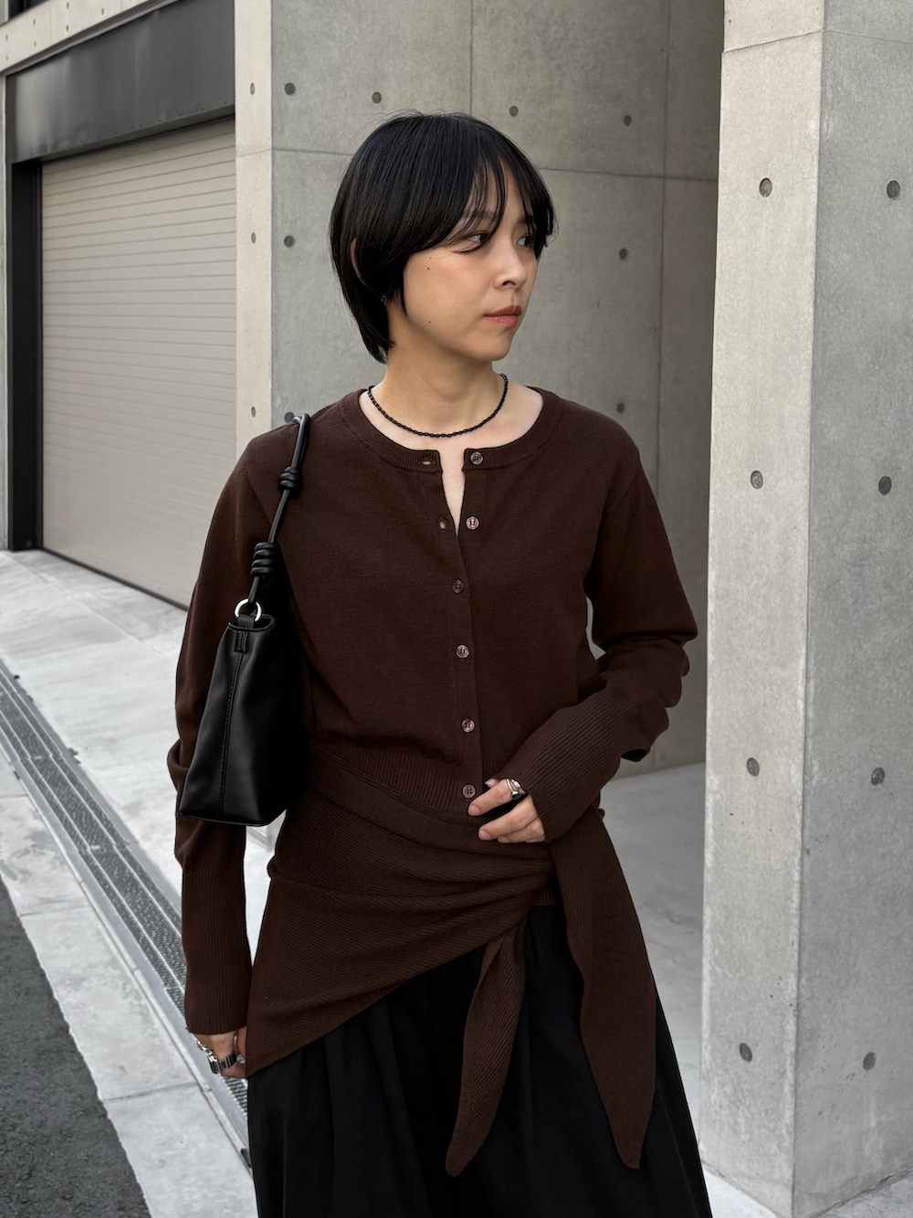 ブラック系のハンドバッグ、ブラウン系のカーディガン/ボレロ、ブラック系のその他パンツを着用したレディースの秋コーディネートの3枚目の写真