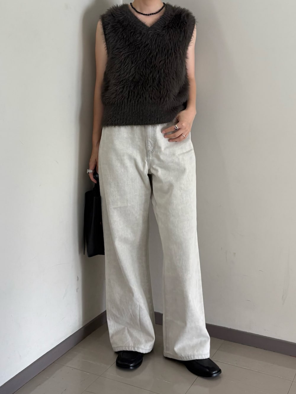 グレー系のベスト、ブラック系のトートバッグ、グレー系のデニムパンツを着用したレディースの夏コーディネートの2枚目の写真