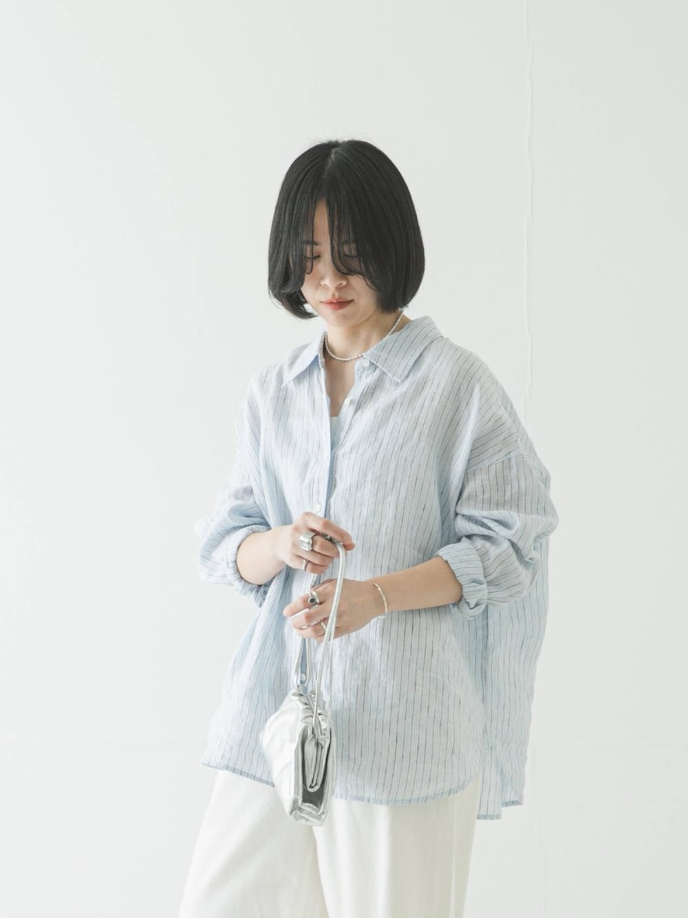 ブルー系のシャツ/ブラウス、シルバー系のショルダーバッグ、ホワイト系のデニムパンツを着用したレディースの春コーディネートの3枚目の写真