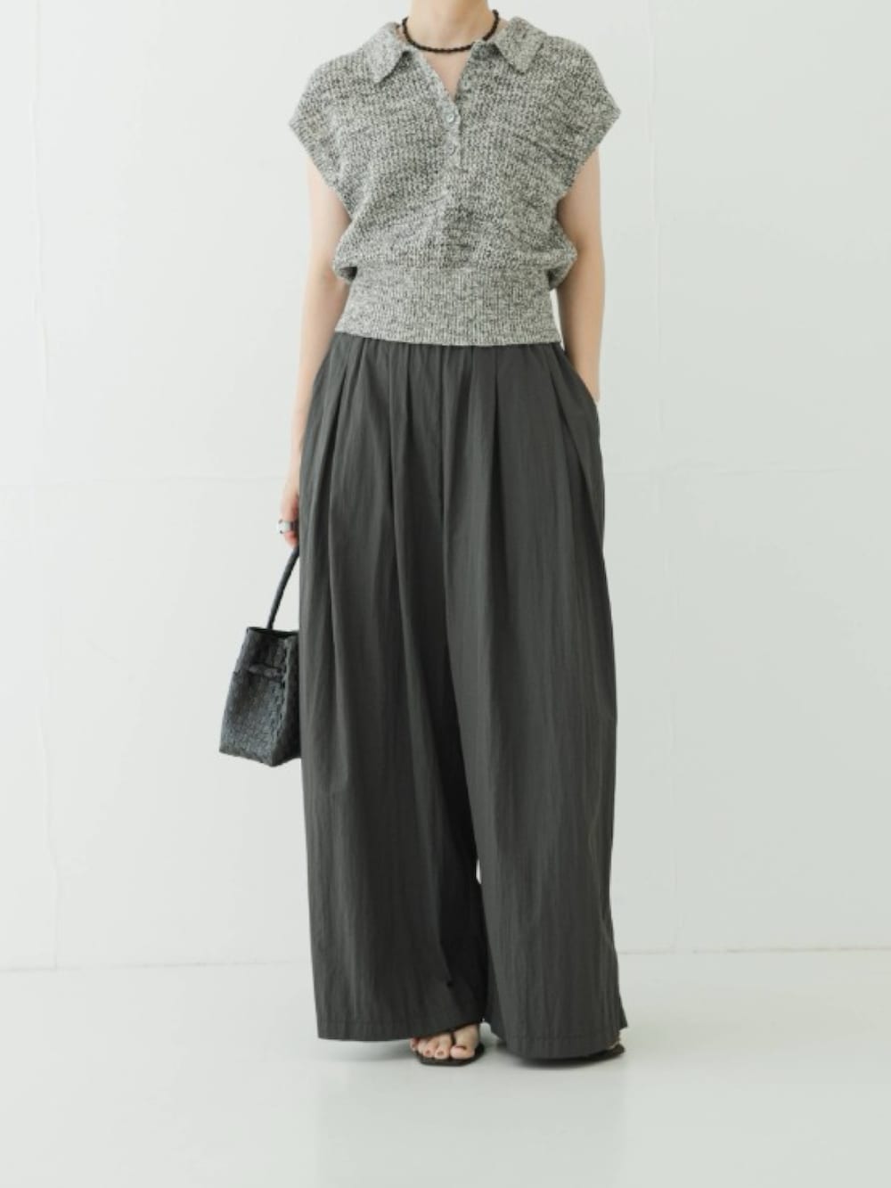 ブラック系のニット/セーター、グレー系のその他パンツ、ブラック系のトートバッグを着用したレディースの夏コーディネートの2枚目の写真