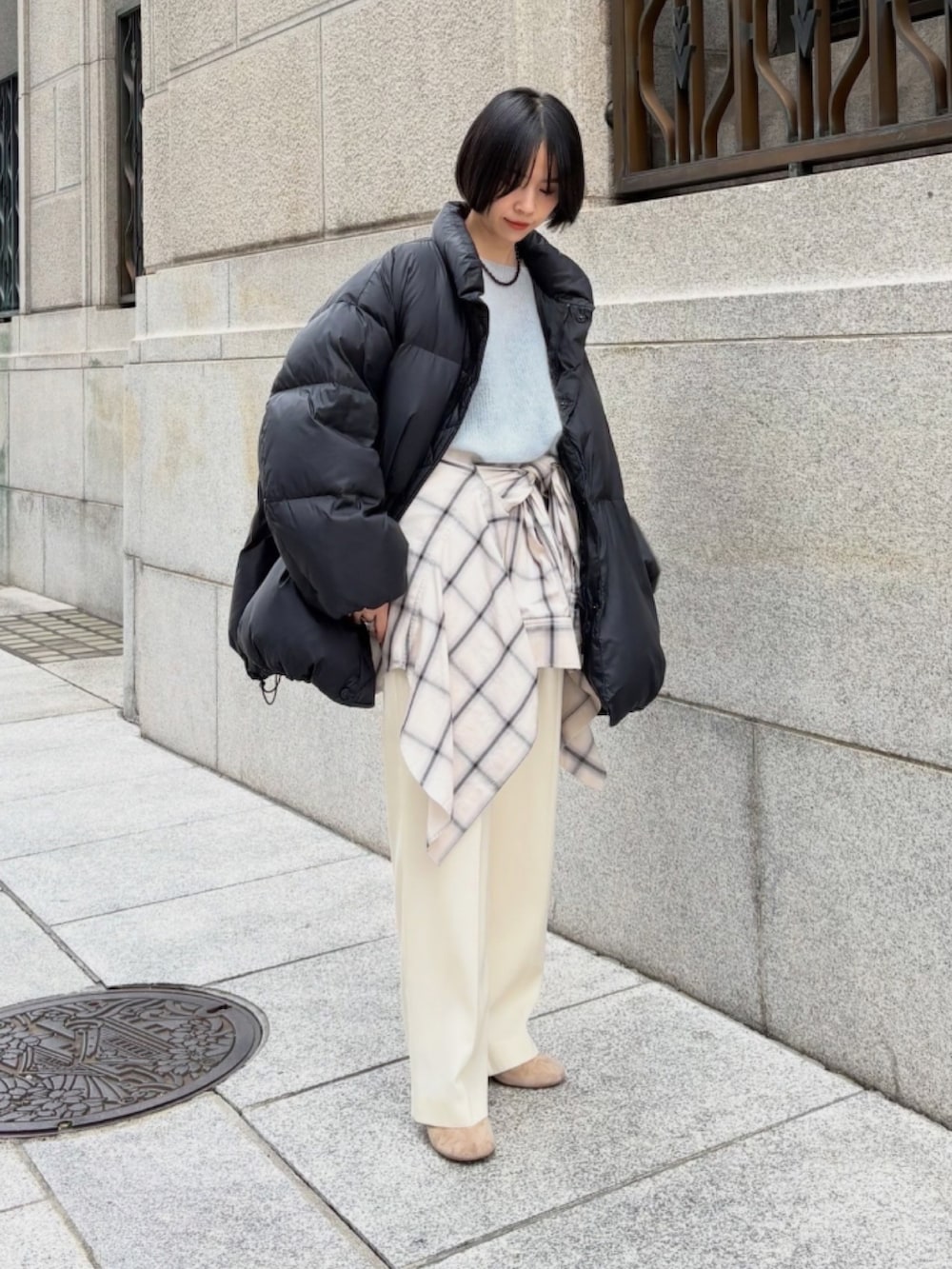 ベージュ系のブーツ、ブルー系のニット/セーター、ブラック系のダウンジャケット/コートを着用したレディースの秋コーディネートの2枚目の写真