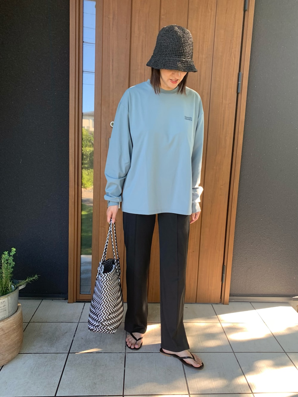 その他のかごバッグ、ブラック系のサンダル、ブラック系の帽子を着用したレディースの夏コーディネートの3枚目の写真