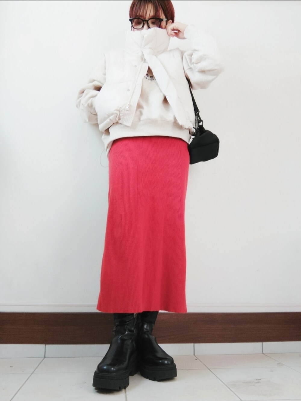 ホワイト系のダウンベスト、ブラック系のショルダーバッグ、グレー系のTシャツ/カットソーを着用したレディースの冬コーディネートの2枚目の写真