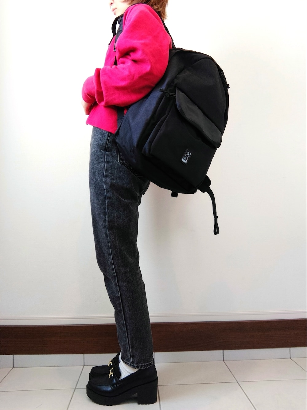 ブルー系のニット/セーター、レッド系のカーディガン/ボレロ、ブラック系のデニムパンツを着用したレディースの冬コーディネートの2枚目の写真