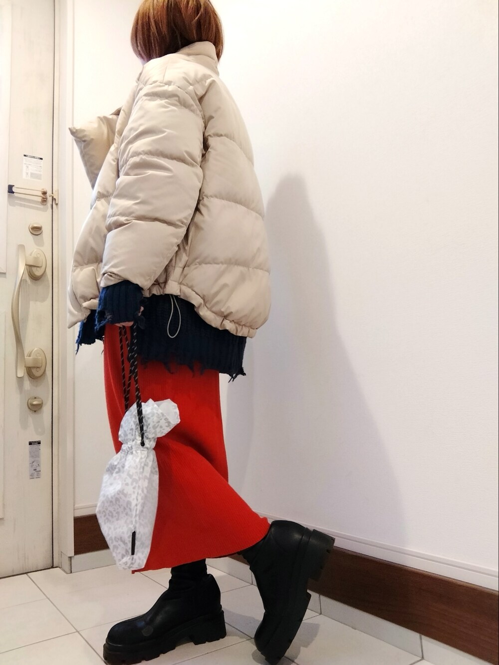 ホワイト系のショルダーバッグ、ベージュ系のダウンジャケット/コート、ブルー系のニット/セーターを着用したレディースの冬コーディネートの2枚目の写真