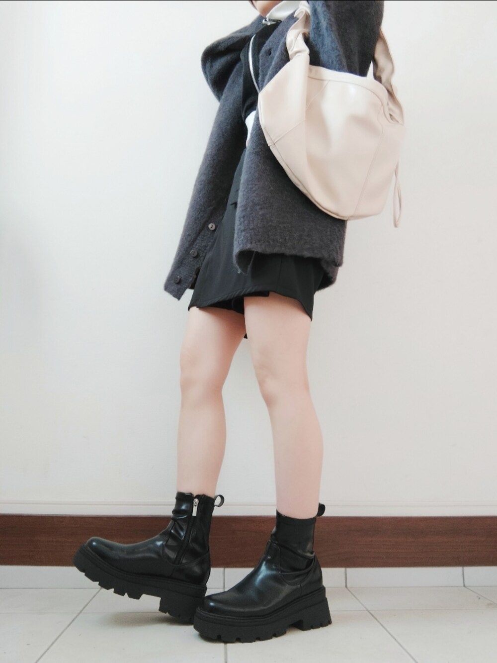 ブラック系のジャージ、グレー系のカーディガン/ボレロ、ブラック系のスカートを着用したレディースの秋コーディネートの2枚目の写真