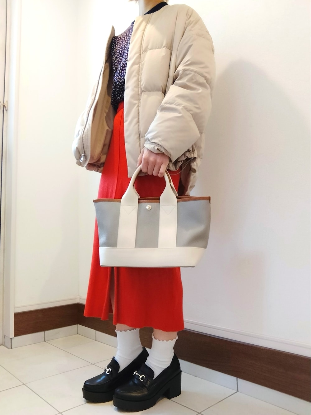 ブルー系のニット/セーター、ベージュ系のダウンジャケット/コート、グレー系のトートバッグを着用したレディースの冬コーディネートの2枚目の写真