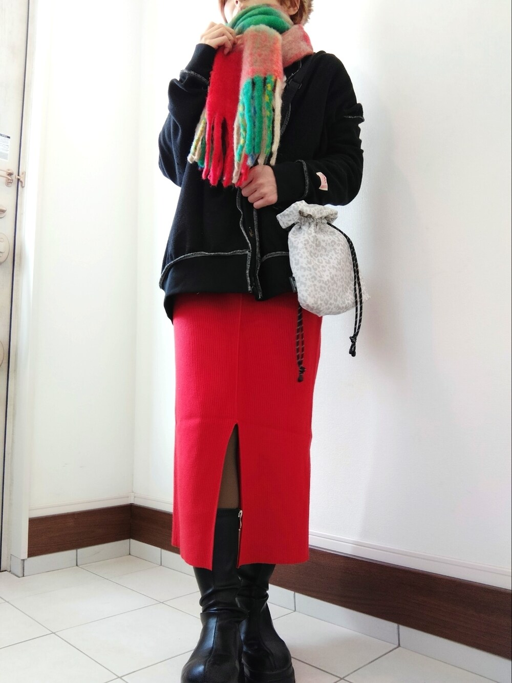 グリーン系のミリタリージャケット、レッド系のスカート、ブラック系のブーツを着用したレディースの冬コーディネートの2枚目の写真