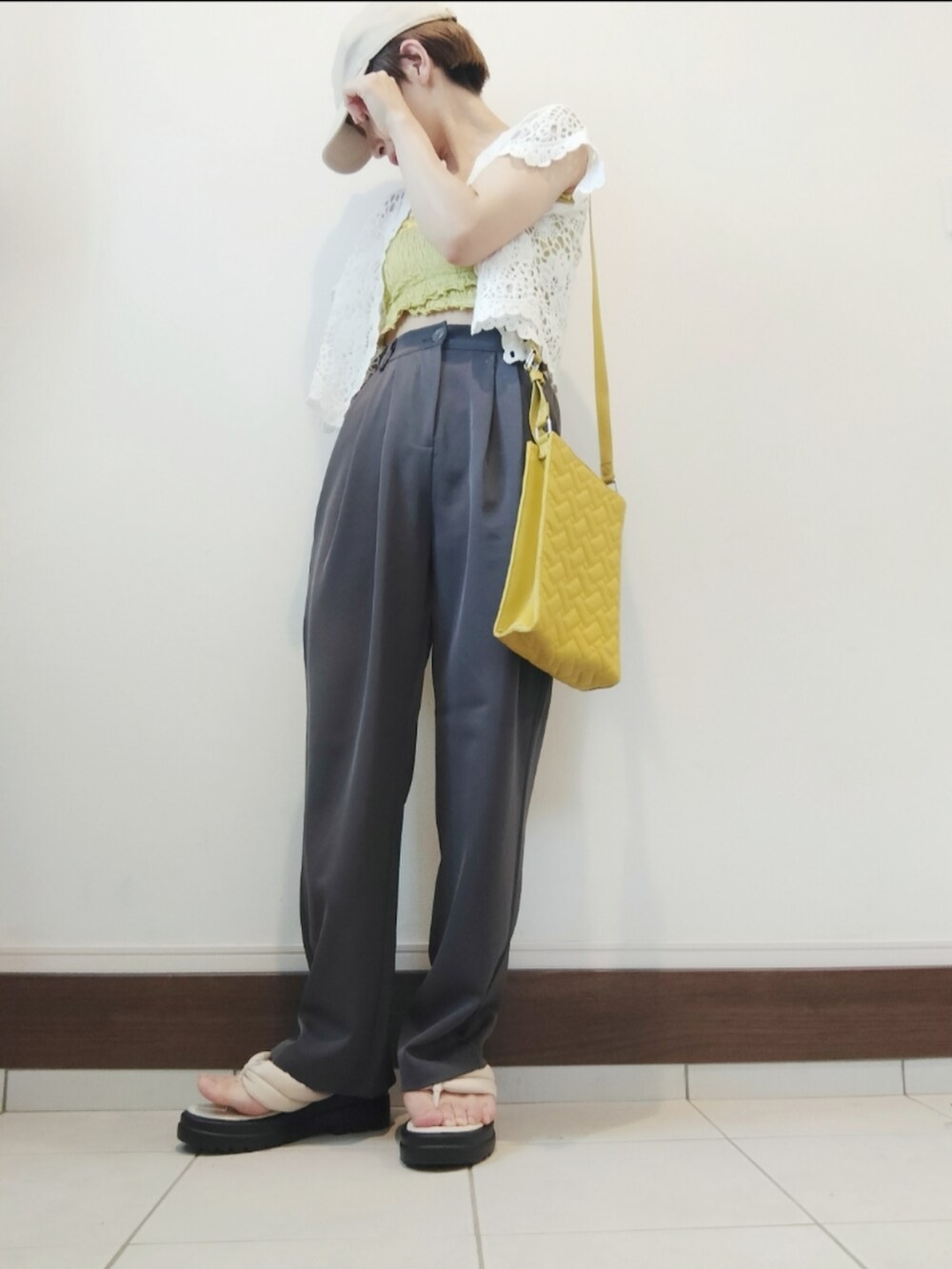 グリーン系のキャミソール、ホワイト系のカーディガン/ボレロ、イエロー系のショルダーバッグを着用したレディースの夏コーディネートの2枚目の写真