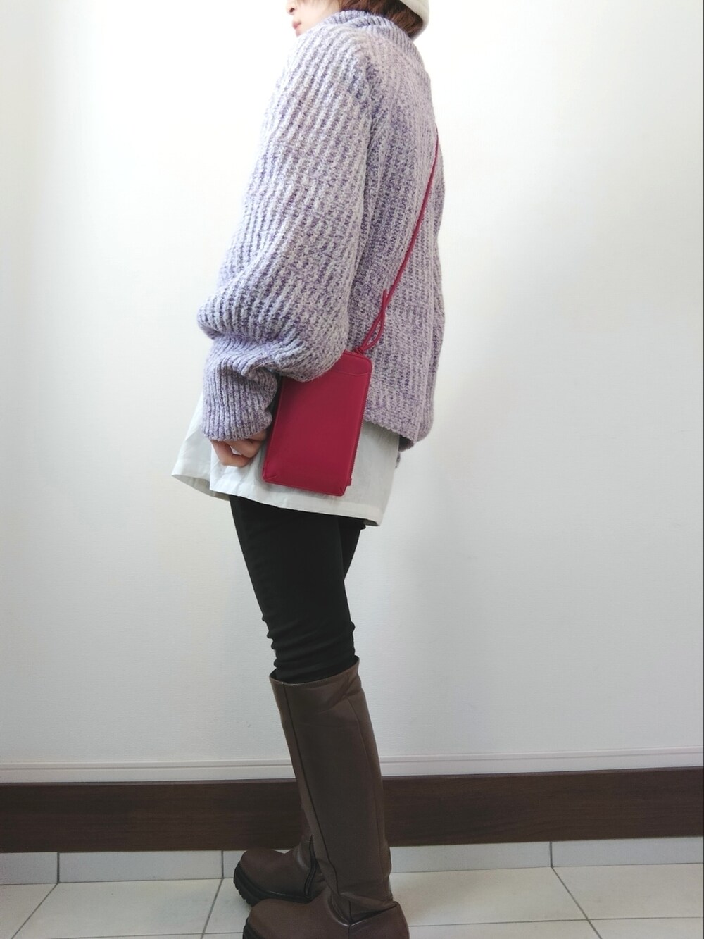 ピンク系のショルダーバッグ、パープル系のニット/セーター、ブラック系のデニムパンツを着用したレディースの冬コーディネートの2枚目の写真