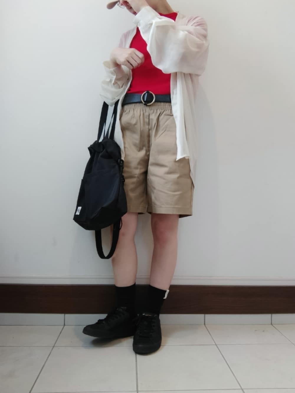 ブラック系のショルダーバッグ、レッド系のTシャツ/カットソー、ベージュ系のカーゴパンツを着用したレディースの春コーディネートの2枚目の写真